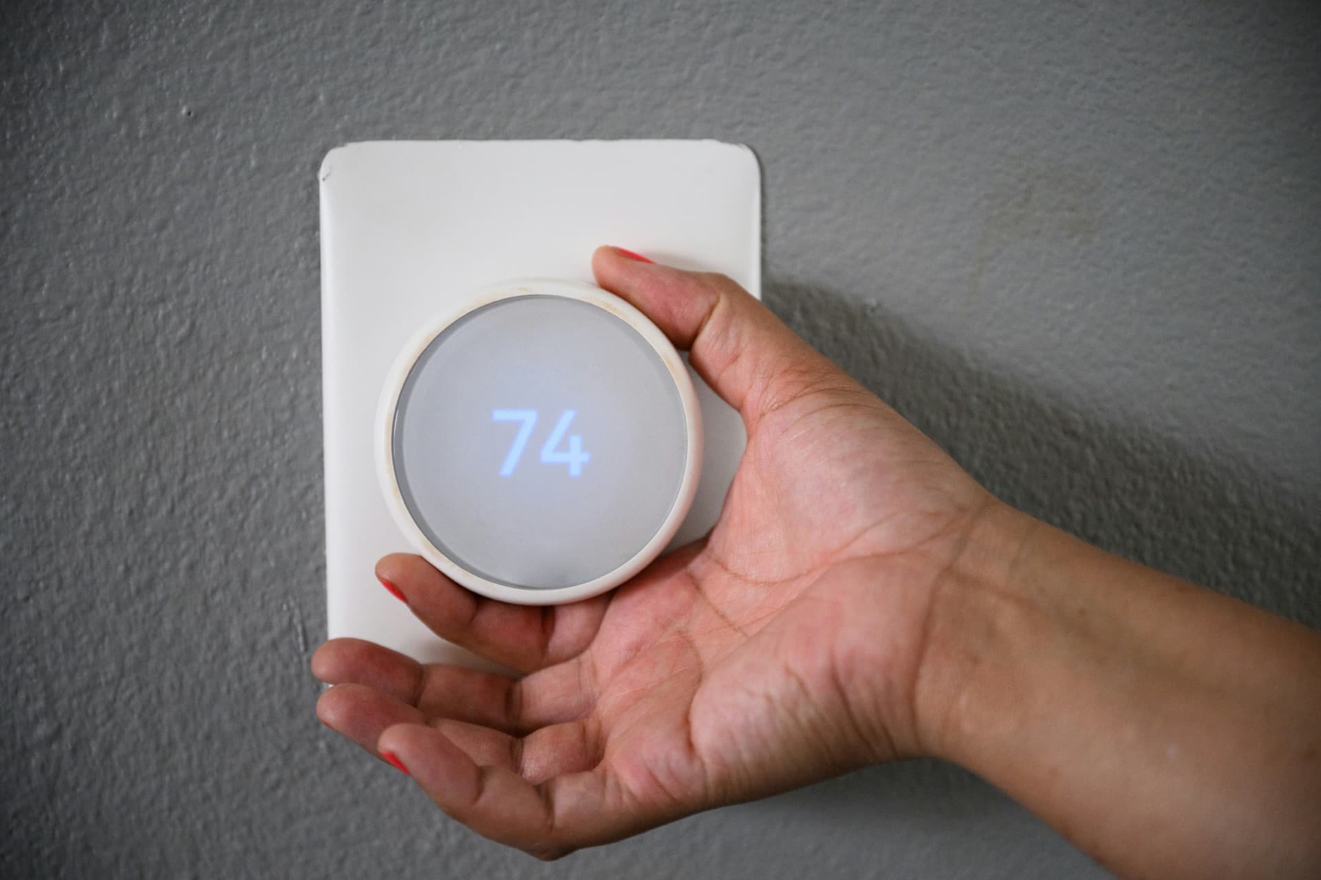 Hand adjusting a smart thermostat on a wall
